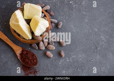 Burro di cacao o olio solido di fagioli di cacao e fagioli di cacao crudi sullo sfondo rustico, olio naturale sano Foto Stock