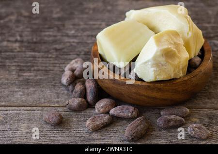 Burro di cacao o olio solido di fagioli di cacao e fagioli di cacao crudi sullo sfondo rustico, olio naturale sano Foto Stock