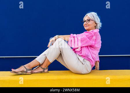 Bella donna anziana felice che indossa abiti casual colorati in posa su sfondo colorato, concetti su anziani e stile di vita Foto Stock