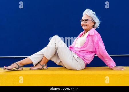 Bella donna anziana felice che indossa abiti casual colorati in posa su sfondo colorato, concetti su anziani e stile di vita Foto Stock