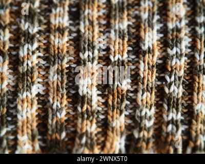 Tela a maglia o a uncinetto. Maglia con stile - gomma lavorata a maglia. Fili bianchi, grigi, marroni, beige. Uno schema di ondulazione. Macchina viscosa Foto Stock