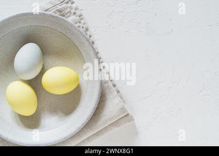 Foto in alto di uova di Pasqua colorate in un piatto di ceramica con spazio per le copie Foto Stock