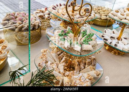 Foto orizzontale un sontuoso spettacolo di dolci arabi, caratterizzato da una varietà di texture e sapori, presentati su squisiti banchi dorati con intricati piatti Foto Stock