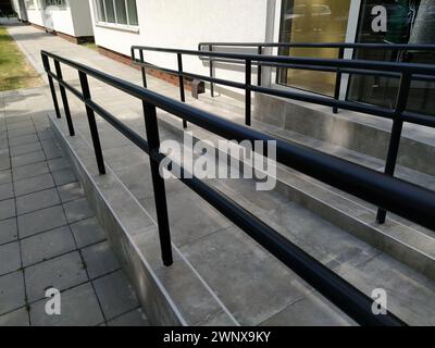 Rampe per disabili accanto all'ingresso dell'edificio. Nuova scuola attrezzata secondo gli standard moderni. Ambiente accessibile. Dispositivi per persone con Foto Stock