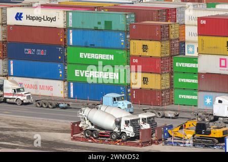 Puerto Quetzal, Guatemala - 19 gennaio 2024: Container impilati nel porto della città con nuove betoniere sulle piattaforme di trasporto Foto Stock