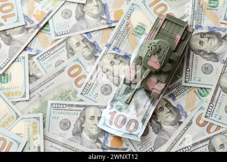 Carro armato su banconote da cento dollari schiacciate. Contesto del finanziamento di guerra e del prezzo di supporto militare per gli Stati Uniti d'America Foto Stock