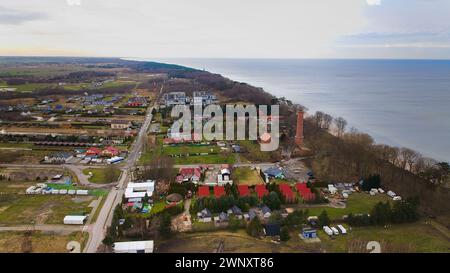 Un drone mostra la spiaggia di Gąski, il voivodato della Pomerania Occidentale, Polonia, con un faro di mattoni rossi, il Mar Baltico, la spiaggia sabbiosa, gli alberi di dune senza foglie, hol Foto Stock