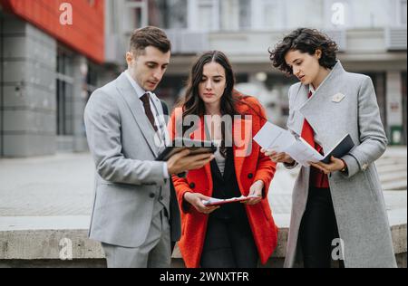 Tre giovani soci d'affari in una riunione informale fuori da un moderno edificio di uffici, con idee di brainstorming. Foto Stock