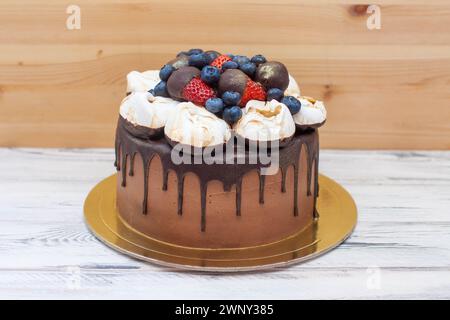 Torta di compleanno al cioccolato con gocciolatoio di ganache al cioccolato, nuvole di meringa e frutti di bosco freschi Foto Stock