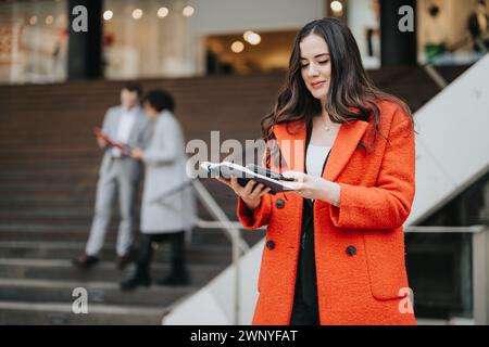 Donna d'affari sicura con un tablet davanti ai colleghi che discutono di lavoro Foto Stock