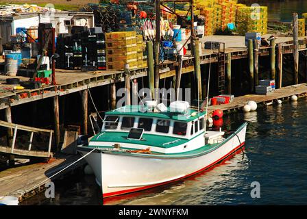 Una barca commerciale con aragosta è attraccata con la bassa marea circondata da trappole per aragosta sulla costa di Portsmouth, New Hampshire Foto Stock