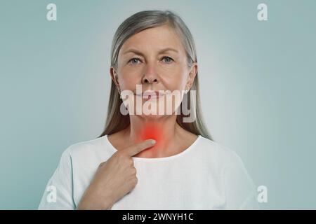 Sistema endocrino. Donna che fa l'autoesame della tiroide su sfondo azzurro Foto Stock