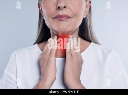 Sistema endocrino. Donna che fa l'autoesame della tiroide su sfondo grigio, primo piano Foto Stock