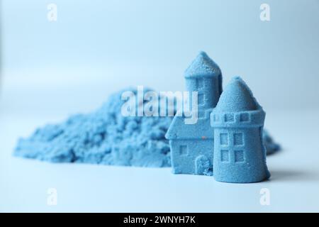 Figure del castello fatte di sabbia cinetica su sfondo azzurro, primo piano. Spazio per il testo Foto Stock