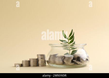 Risparmi finanziari. Monete, ramoscelli e vasetti in vetro su sfondo beige Foto Stock