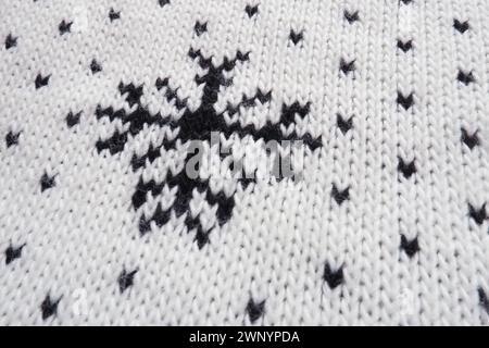 Motivo jacquard lavorato a maglia. Ornamento geometrico per Natale o Capodanno. Fiocchi di neve neri lavorati a maglia e puntini su sfondo bianco. Moderno e alla moda d'inverno Foto Stock