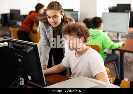 L'insegnante insieme agli studenti conduce una lezione sull'educazione informatica Foto Stock