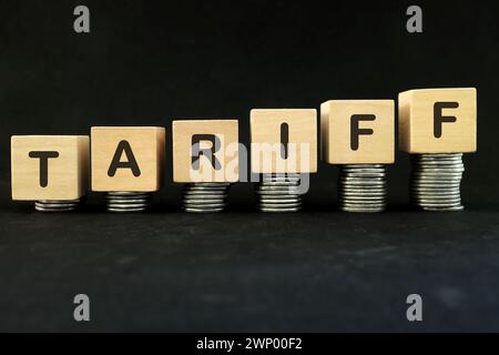 Aumentare il concetto di imposta tariffaria. Parola in blocchi di legno con una pila crescente di monete. Foto Stock