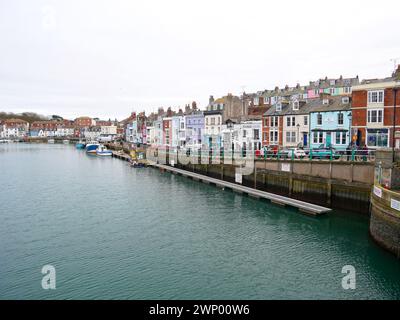 Barche da pesca sul fiume al porto di Weymouth nel Dorset, in Inghilterra, con vecchi edifici lungo Trinity Road. Foto Stock