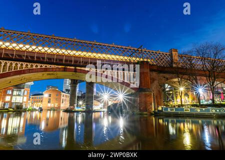 Foto a lunga esposizione del ponte di Manchester Castlefield e di un treno che passa sopra di esso. Foto Stock