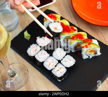 Involtini di sushi con uramaki con salmone e gamberi norimaki su tavola di ardesia Foto Stock