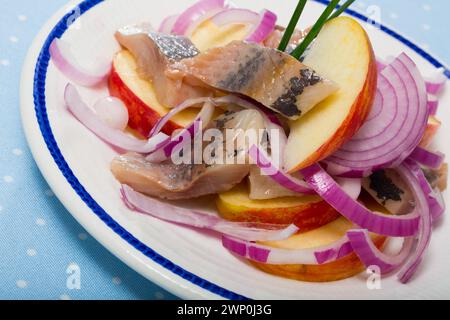 Sono servite fette di aringa leggermente curata con patate fritte e cipolle Foto Stock