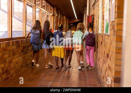 Gruppo di studentesse diverse che camminano in un corridoio a scuola Foto Stock