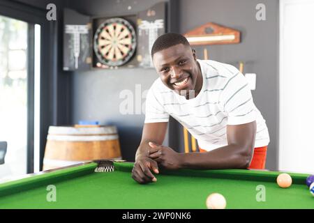 Il giovane afroamericano sorride mentre si appoggia su un tavolo da biliardo Foto Stock