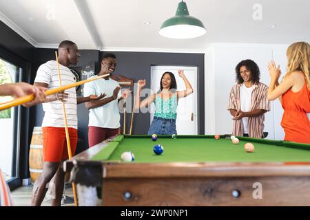 Gruppi di amici diversi si divertono a giocare a biliardo in una stanza luminosa Foto Stock