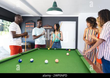 Gruppi diversi di amici si divertono a giocare a biliardo in un ambiente domestico Foto Stock