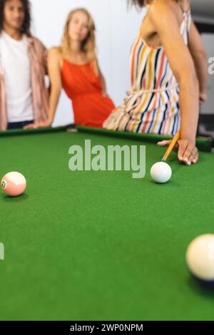 La concentrazione è su un tavolo da biliardo con le palle in una configurazione di gioco, con una donna che scatta un colpo Foto Stock