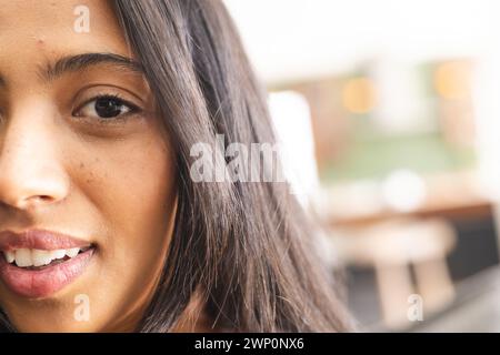 Primo piano di una giovane donna birazziale con gli occhi marroni e lunghi capelli scuri, con spazio di copia Foto Stock