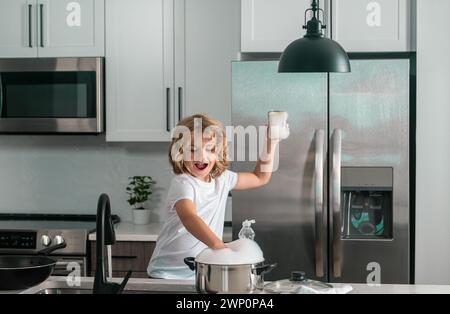 Divertenti ragazzi gemelli che aiutano in cucina con piatti di lavaggio. Bambini che si divertono con i lavori di casa. Aiuto per bambini nel lavaggio dei piatti in cucina. Foto Stock