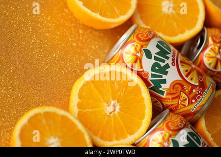 KIEV, UCRAINA - 7 LUGLIO 2023 bevanda all'arancia Mirinda con molte arance fresche su sfondo colorato Foto Stock