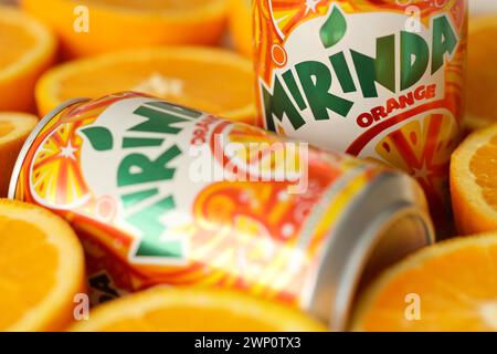 KIEV, UCRAINA - 7 LUGLIO 2023 bevanda all'arancia Mirinda con molte arance fresche su sfondo colorato Foto Stock