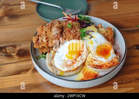 Un piatto di pollo fritto e uova con un contorno di verdure. Il piatto è su un tavolo di legno Foto Stock