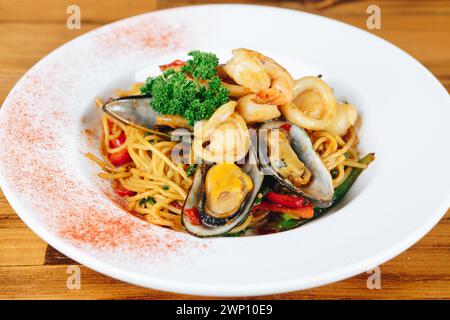 Un piatto di cibo con un piatto bianco e un bordo rosso. Il cibo è un mix di frutti di mare e verdure Foto Stock