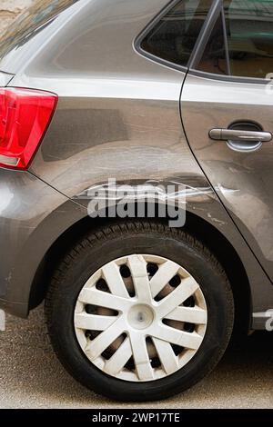 Parafango posteriore rotto graffiato. Graffiato con danni profondi alla vernice. La vettura da vicino con un parafango danneggiato è parcheggiata sul lato della strada, con Foto Stock
