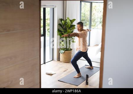 L'anziano birazziale pratica yoga in un luminoso e moderno soggiorno con spazio fotocopie Foto Stock