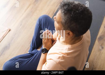 Senior birazziale con capelli grigi pratica yoga in un ambiente interno sereno Foto Stock