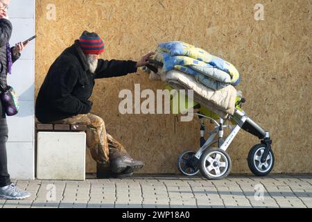 Un anziano senzatetto che vive per strada con effetti personali in un passeggino anziano anziano Foto Stock