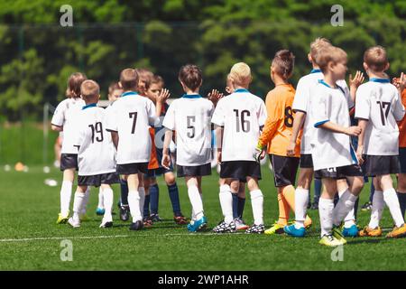 I ragazzi giocatori di calcio si ringraziano a vicenda per aver giocato dopo la fine della competizione. I bambini giocano a sport su un campo di erba. Football bambini fair play Behavior af Foto Stock