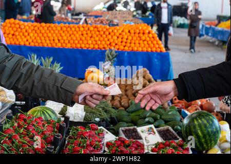 Un uomo che paga per fare shopping in un mercato locale. Foto Stock