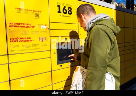 Augsburg, Baviera, Germania - 25 febbraio 2024: Un uomo rispedisce un pacco con ritorno Zalando utilizzando una Packstation DHL *** Ein Mann schickt ein Paket mit einer Zalando Retoure mit einer DHL Packstation Zurück Foto Stock