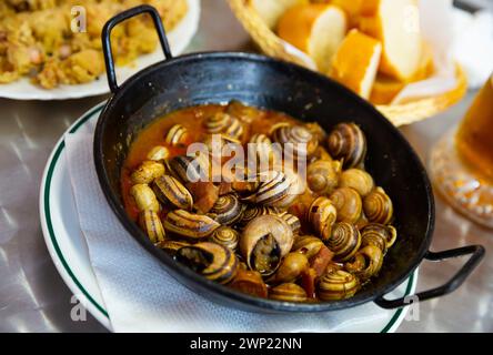Cottura delle lumache d'uva in salsa piccante. Piatto tradizionale spagnolo Foto Stock