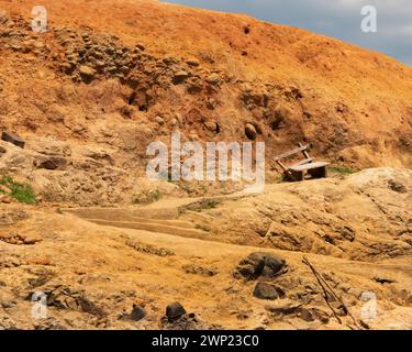 Vecchia panchina di legno crollata e fatiscente su uno stretto sentiero in una collina arida a Panama che mostra un deserto secco come un paesaggio senza persone Foto Stock