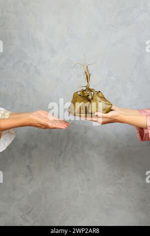 Ketupat condiviso, due donne che condividono la torta di riso a forma di diamante per la celebrazione di Eid al Fitr Foto Stock