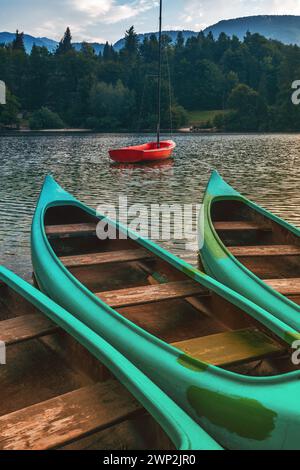 Tre canoe verdi e gommone rosso sul lago Bohinj, concentrazione selettiva Foto Stock