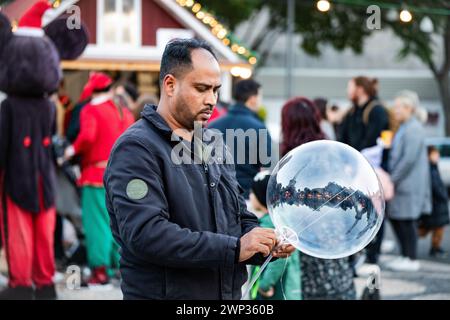 Uomo che soffia bolle al mercatino di natale annuale Foto Stock