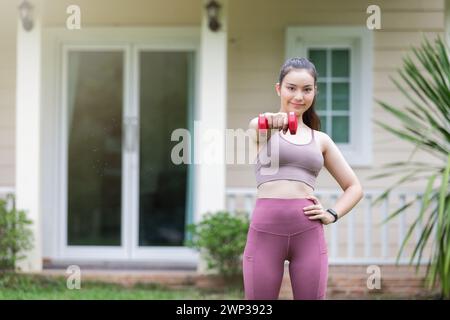 Istruttore di fitness femminile che si esercita con il piccolo manubri sul cortile. Foto Stock